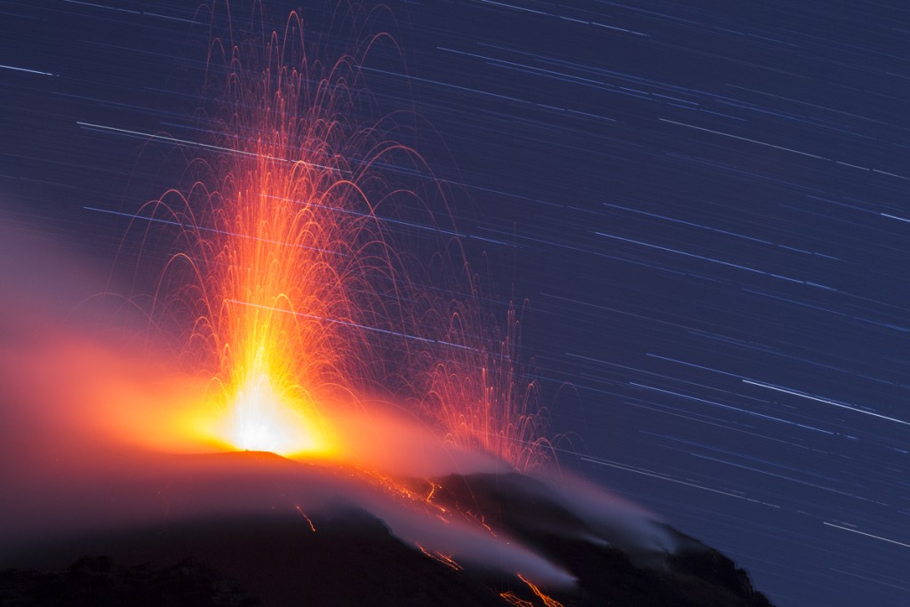 Volcán en erupción con cielo estrellado